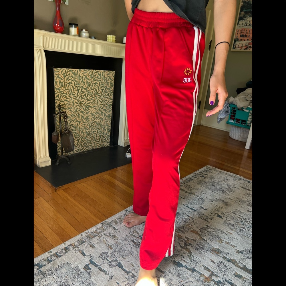 Urban Outfitters BDG Red track pants with three white stripes on the side.